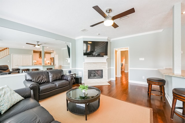 living room with crown molding, dark hardwood / wood-style floors, and ceiling fan