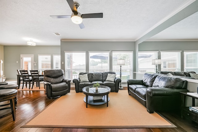 living room featuring a textured ceiling, a healthy amount of sunlight, dark wood-type flooring, and ceiling fan