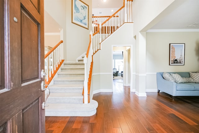 foyer featuring crown molding, hardwood / wood-style flooring, and a high ceiling