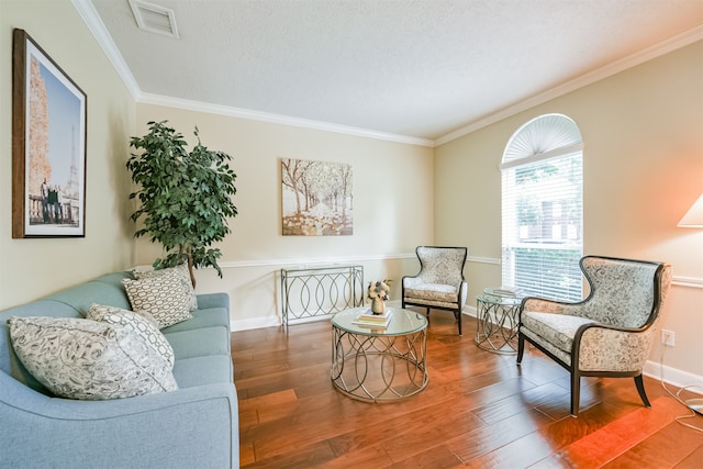 living area featuring crown molding, hardwood / wood-style flooring, and a textured ceiling