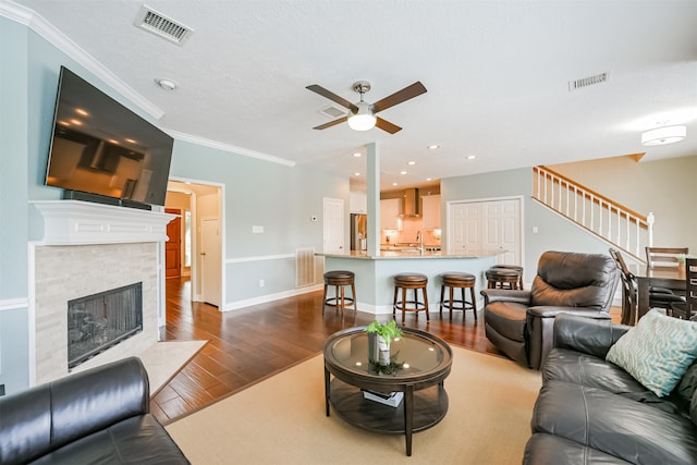 living room featuring ornamental molding, sink, a fireplace, and dark hardwood / wood-style floors