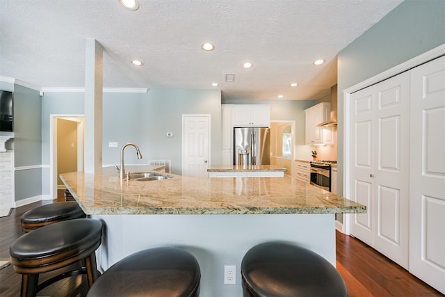 kitchen featuring appliances with stainless steel finishes, white cabinets, sink, and a breakfast bar area