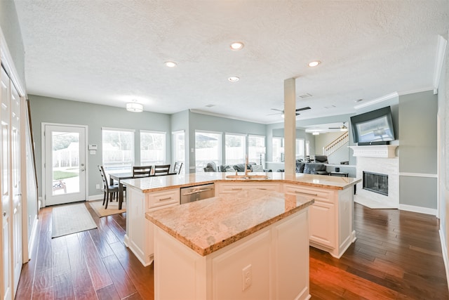 kitchen featuring dishwasher, a kitchen island with sink, dark hardwood / wood-style flooring, a textured ceiling, and ceiling fan