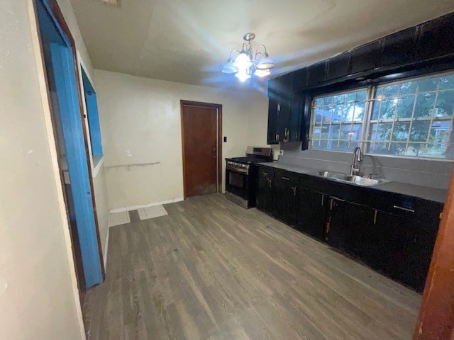 kitchen featuring stainless steel range with gas cooktop, sink, an inviting chandelier, and hardwood / wood-style floors