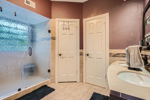 bathroom with vanity, tile walls, a shower with door, and tile patterned floors