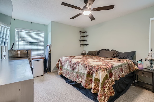 bedroom featuring light carpet, a textured ceiling, and ceiling fan