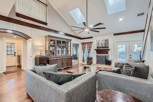 living room with a skylight, ceiling fan, crown molding, high vaulted ceiling, and hardwood / wood-style flooring