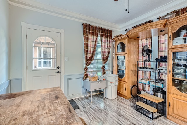 foyer with ceiling fan, a textured ceiling, light hardwood / wood-style floors, and ornamental molding