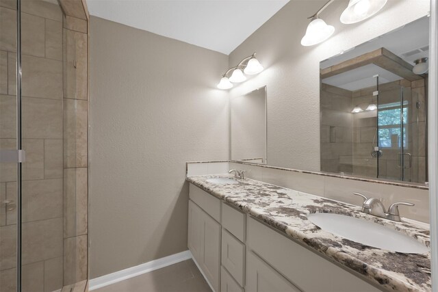 696 Ravensworth Dr, Conroe, TX 77302 - bathroom featuring double vanity, baseboards, a sink, and a stall shower