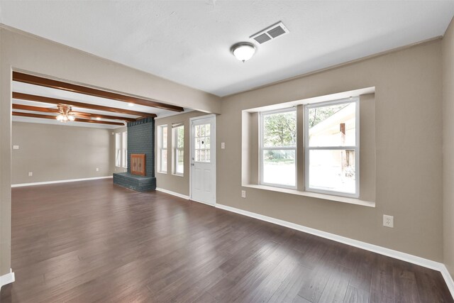 696 Ravensworth Dr, Conroe, TX 77302 - unfurnished living room featuring visible vents, baseboards, dark wood-style flooring, a fireplace, and beam ceiling