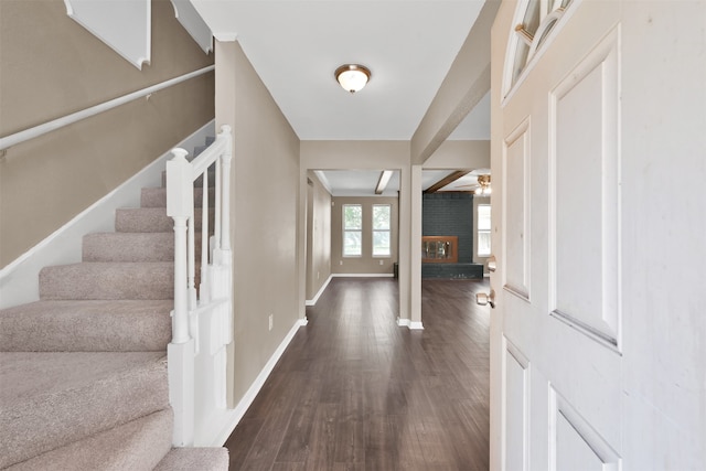 foyer with ceiling fan, a fireplace, and dark wood-type flooring