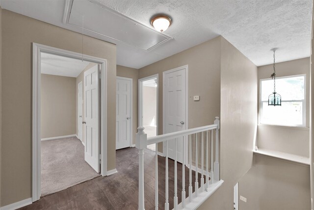696 Ravensworth Dr, Conroe, TX 77302 - corridor with dark wood-style flooring, baseboards, an upstairs landing, a textured ceiling, and attic access