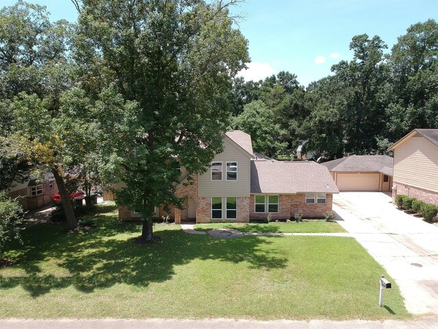 696 Ravensworth Dr, Conroe, TX 77302 - view of front of home with brick siding, a front lawn, an outdoor structure, and concrete driveway