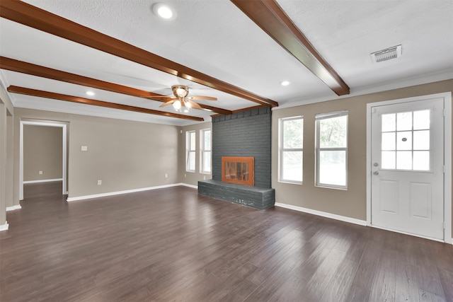 unfurnished living room featuring a brick fireplace, beamed ceiling, dark hardwood / wood-style floors, and a textured ceiling