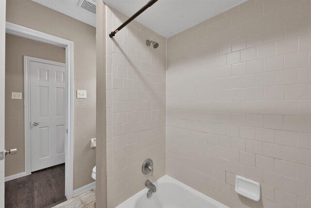 696 Ravensworth Dr, Conroe, TX 77302 - bathroom with visible vents, toilet, baseboards, and washtub / shower combination