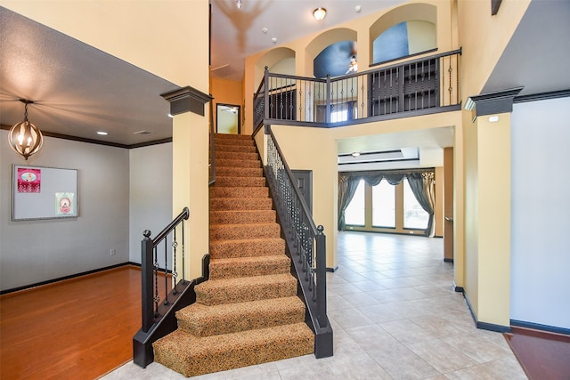 stairs featuring tile patterned floors, crown molding, a high ceiling, and decorative columns