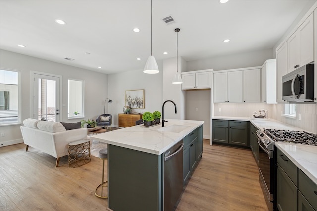 kitchen with a kitchen island with sink, appliances with stainless steel finishes, sink, and white cabinets