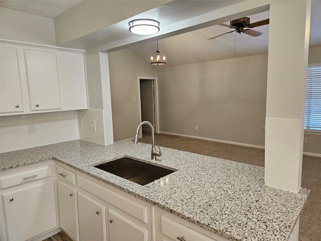 kitchen with hanging light fixtures, sink, white cabinets, and light stone counters