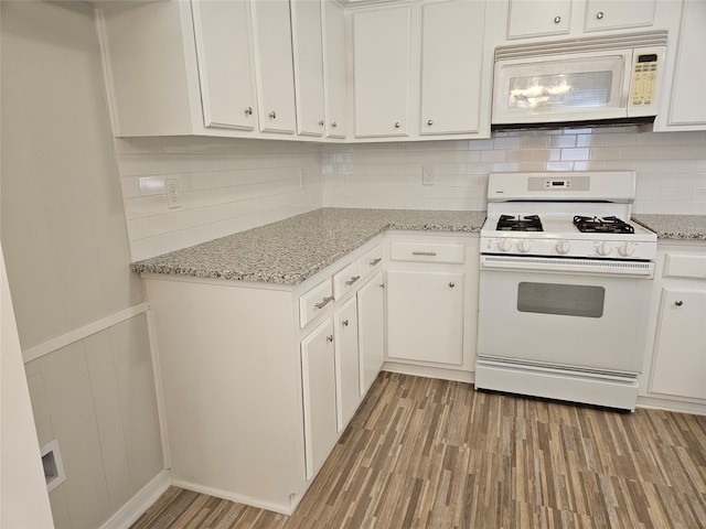 kitchen featuring white cabinets, light hardwood / wood-style flooring, white appliances, and tasteful backsplash