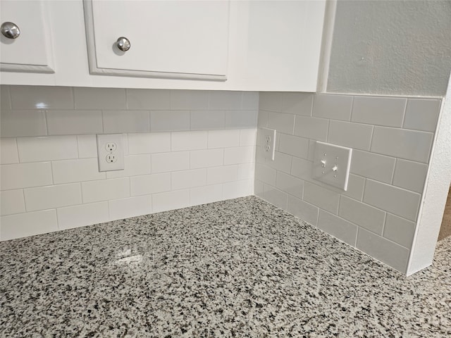 room details with white cabinets and light stone countertops