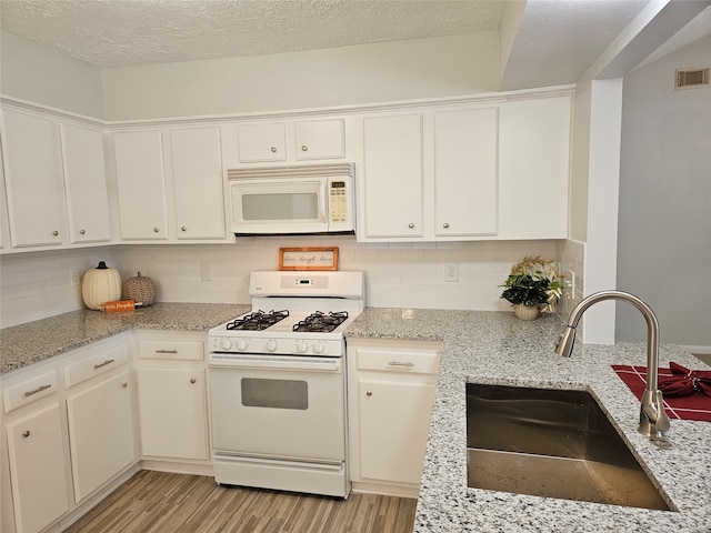 kitchen featuring sink, white cabinets, light wood-type flooring, and white appliances