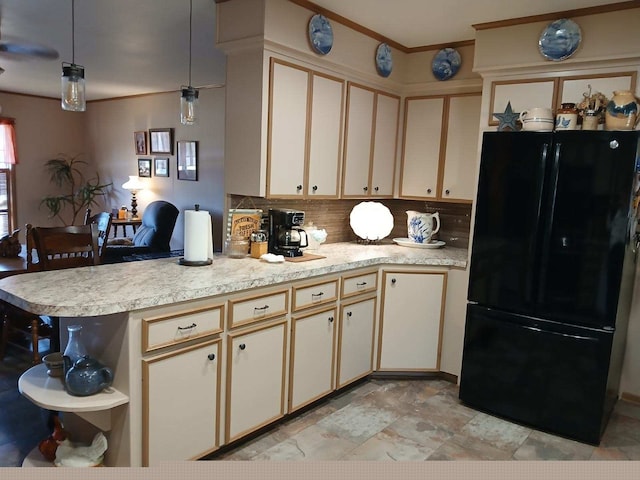 kitchen featuring black fridge, kitchen peninsula, hanging light fixtures, and cream cabinetry