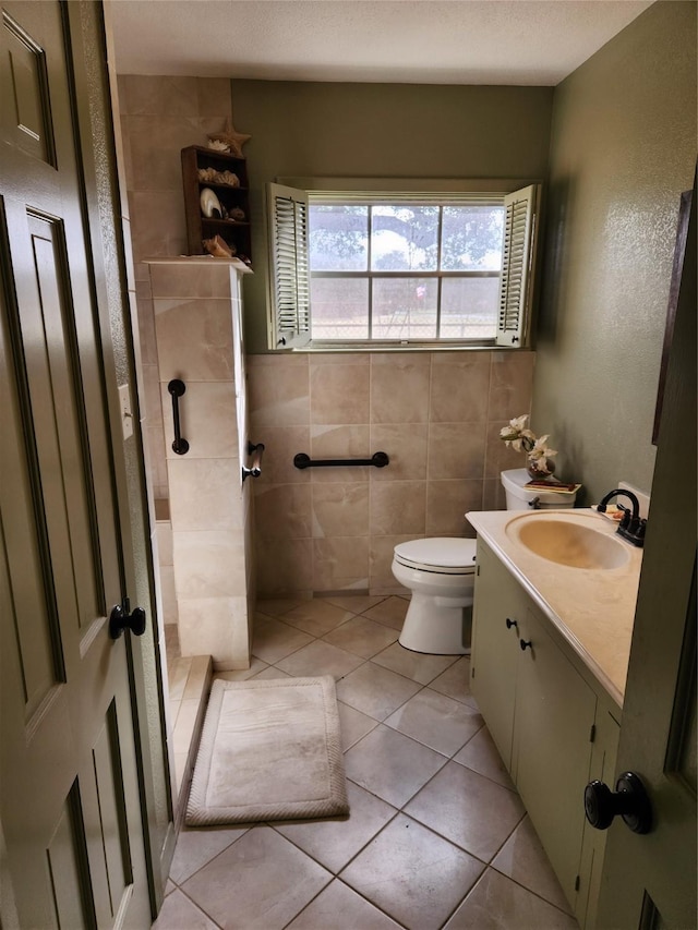 bathroom featuring tile walls, tile patterned flooring, vanity, toilet, and a textured ceiling