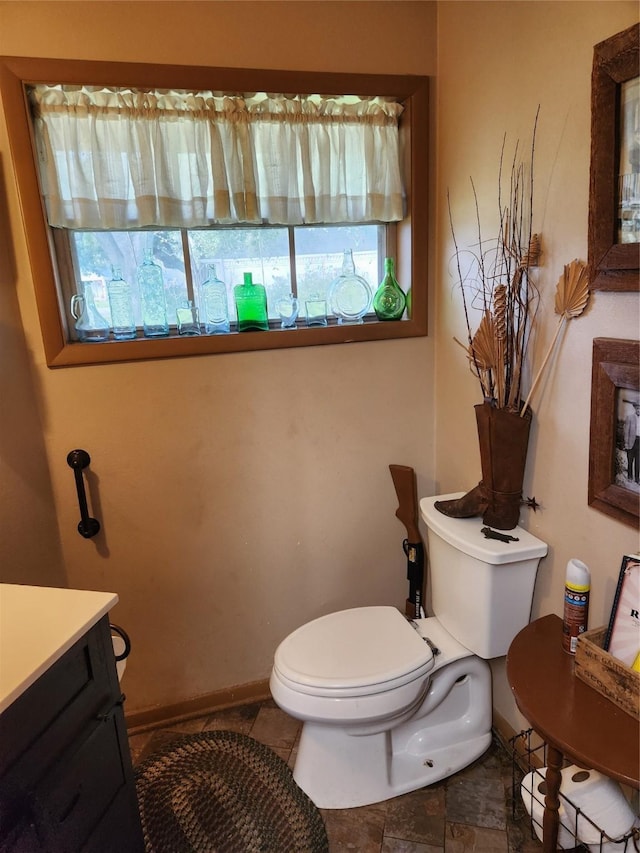 bathroom with plenty of natural light, toilet, and vanity