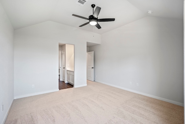 unfurnished bedroom with dark colored carpet, ceiling fan, ensuite bath, and vaulted ceiling