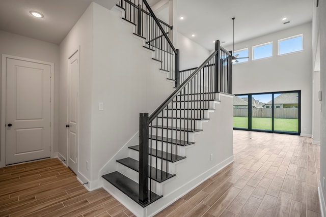 stairway featuring a high ceiling, wood-type flooring, and a chandelier