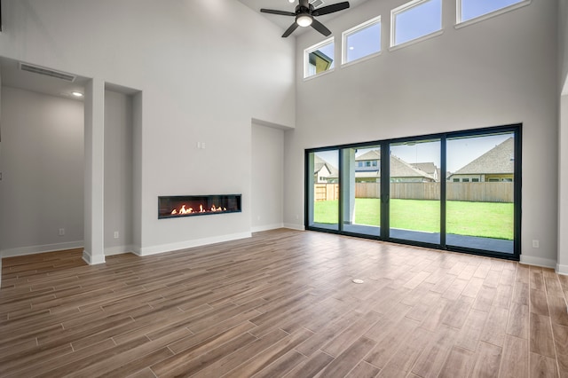 unfurnished living room with hardwood / wood-style floors, a towering ceiling, and plenty of natural light