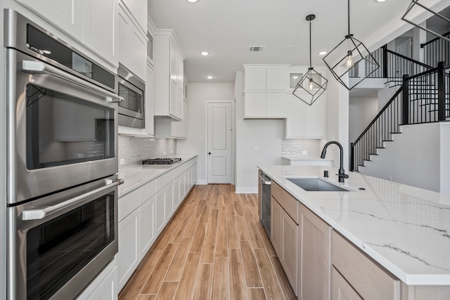 kitchen featuring sink, stainless steel appliances, white cabinets, light stone counters, and light hardwood / wood-style flooring