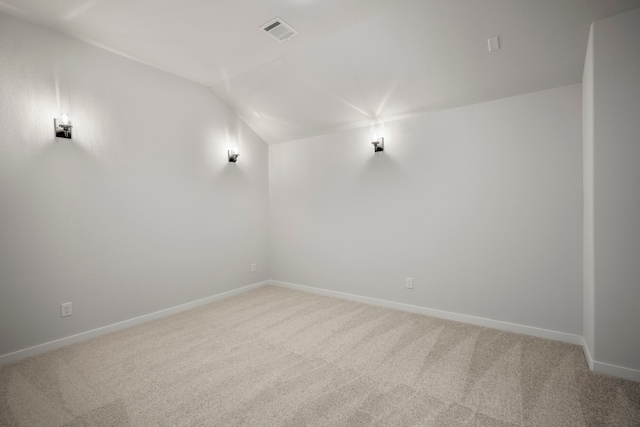 carpeted spare room with vaulted ceiling