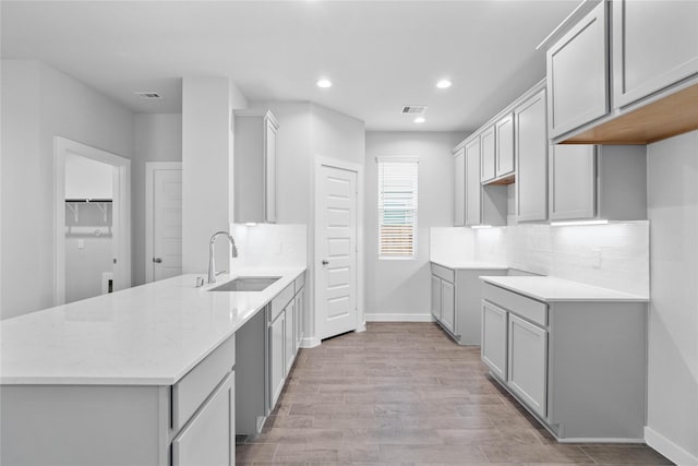 kitchen featuring baseboards, visible vents, a sink, and decorative backsplash