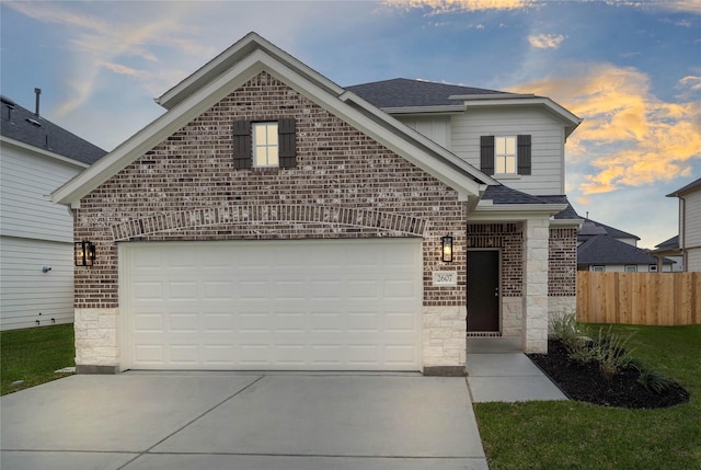 view of front of home featuring a garage, concrete driveway, brick siding, and fence