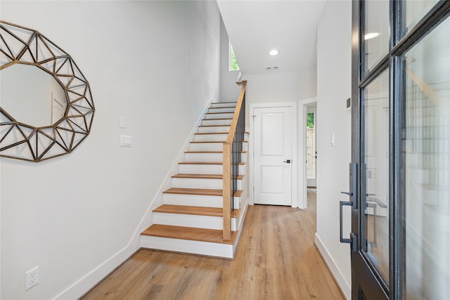 stairs featuring hardwood / wood-style floors and a healthy amount of sunlight