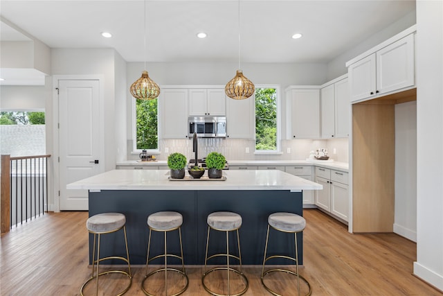 kitchen with light hardwood / wood-style flooring, white cabinetry, a center island, and hanging light fixtures