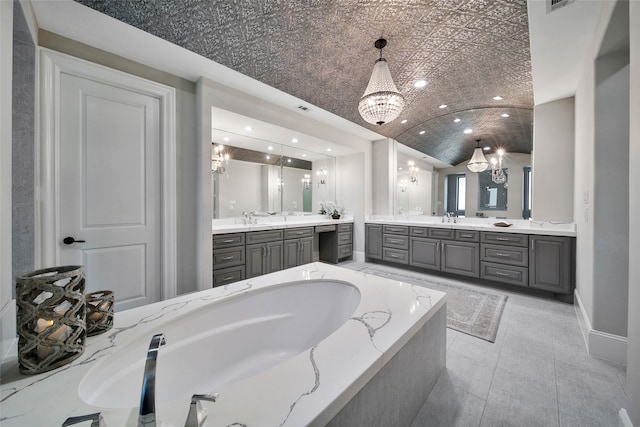 bathroom with a notable chandelier, tile patterned floors, lofted ceiling, a bathtub, and vanity