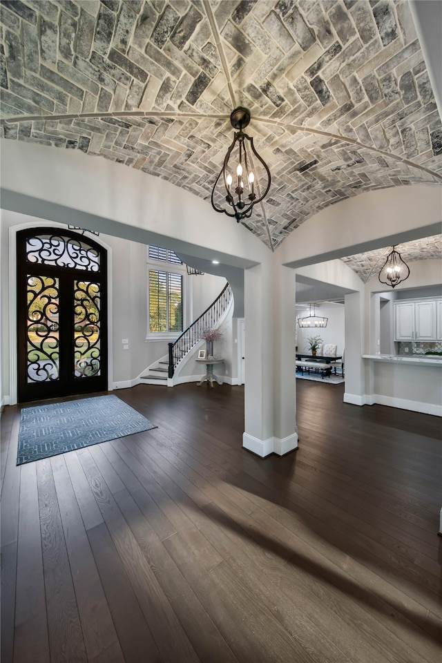 foyer with french doors, dark hardwood / wood-style flooring, brick ceiling, an inviting chandelier, and lofted ceiling