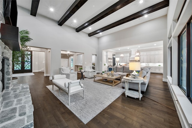 living room featuring a healthy amount of sunlight, a towering ceiling, dark wood-type flooring, and beam ceiling