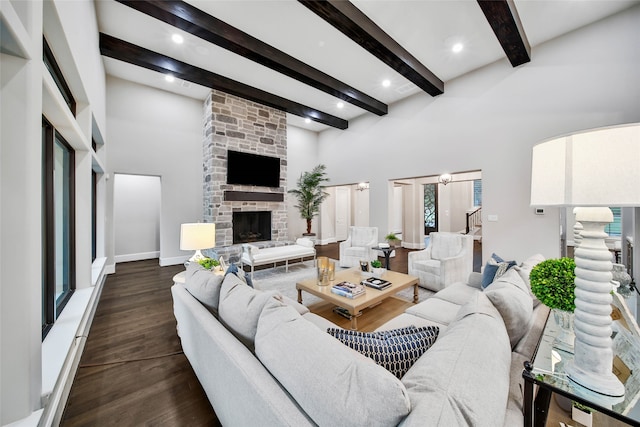 living room with beam ceiling, a stone fireplace, dark wood-type flooring, and a high ceiling