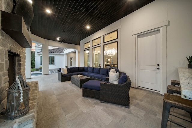 living room featuring an outdoor stone fireplace and wood ceiling