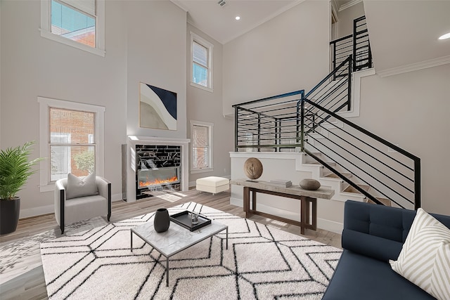 living room featuring hardwood / wood-style flooring, a towering ceiling, and ornamental molding