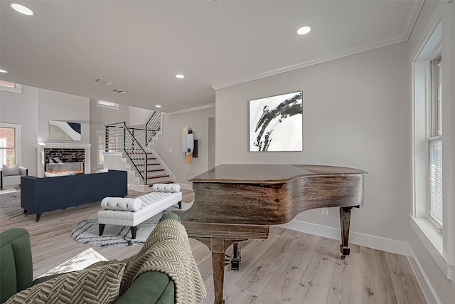 misc room featuring crown molding, a stone fireplace, and light wood-type flooring