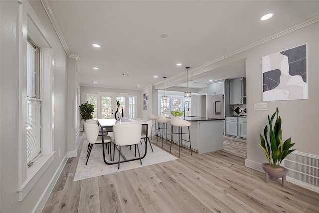 dining space featuring sink, ornamental molding, light hardwood / wood-style flooring, and french doors