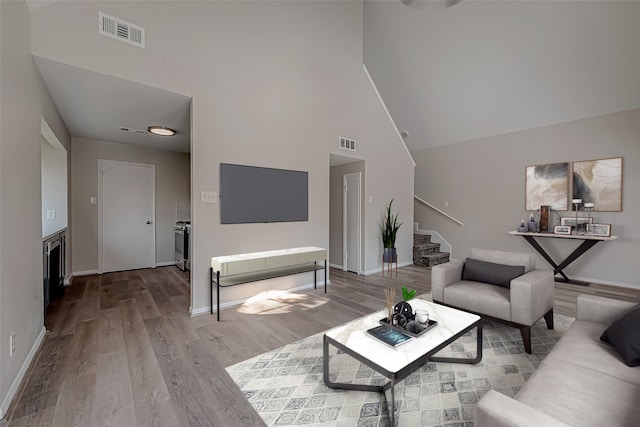 living room with high vaulted ceiling and light hardwood / wood-style flooring