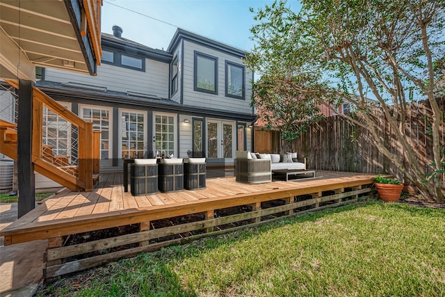 rear view of property with french doors, a deck, a lawn, and outdoor lounge area