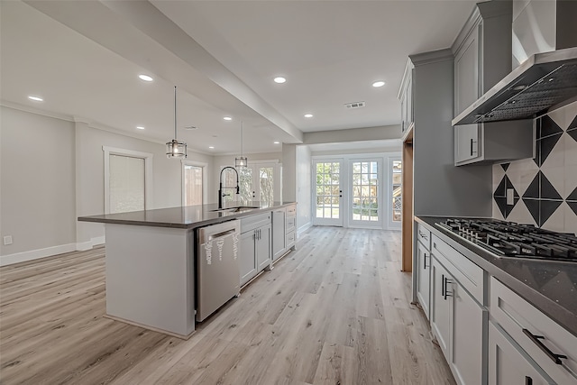 kitchen featuring wall chimney range hood, sink, french doors, stainless steel appliances, and decorative backsplash