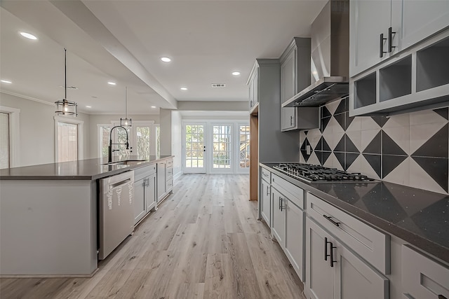 kitchen featuring wall chimney range hood, sink, appliances with stainless steel finishes, french doors, and pendant lighting