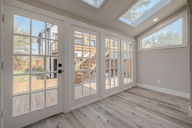 entryway featuring lofted ceiling with skylight, light wood-type flooring, and a healthy amount of sunlight